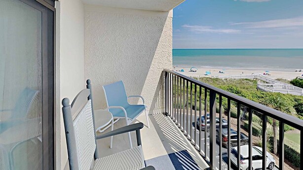 A balcony with a view of the beach and parked cars. - Oceanfront Beach View, Large Pool, Updated! (Pawleys Island)