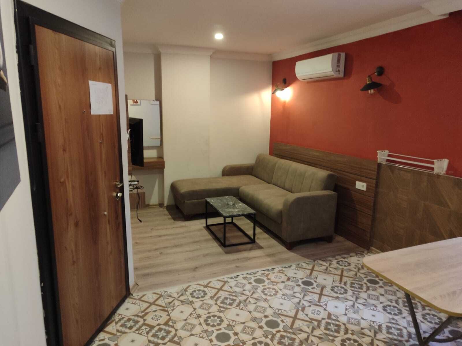 En kompakt opholdsstue med en trædør, en sofa, et lille bord og et gulv med et mønster.