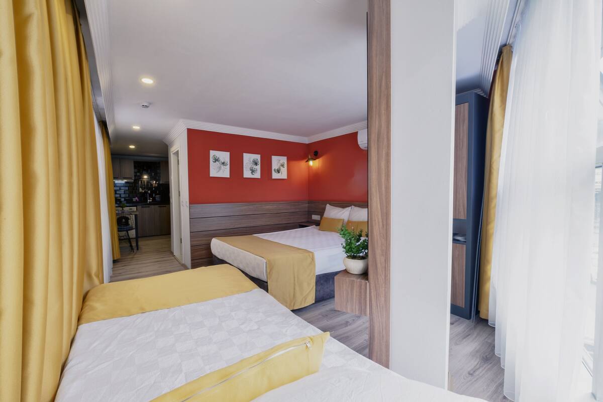 A hotel room with two beds, a small kitchen area, and a dining table.