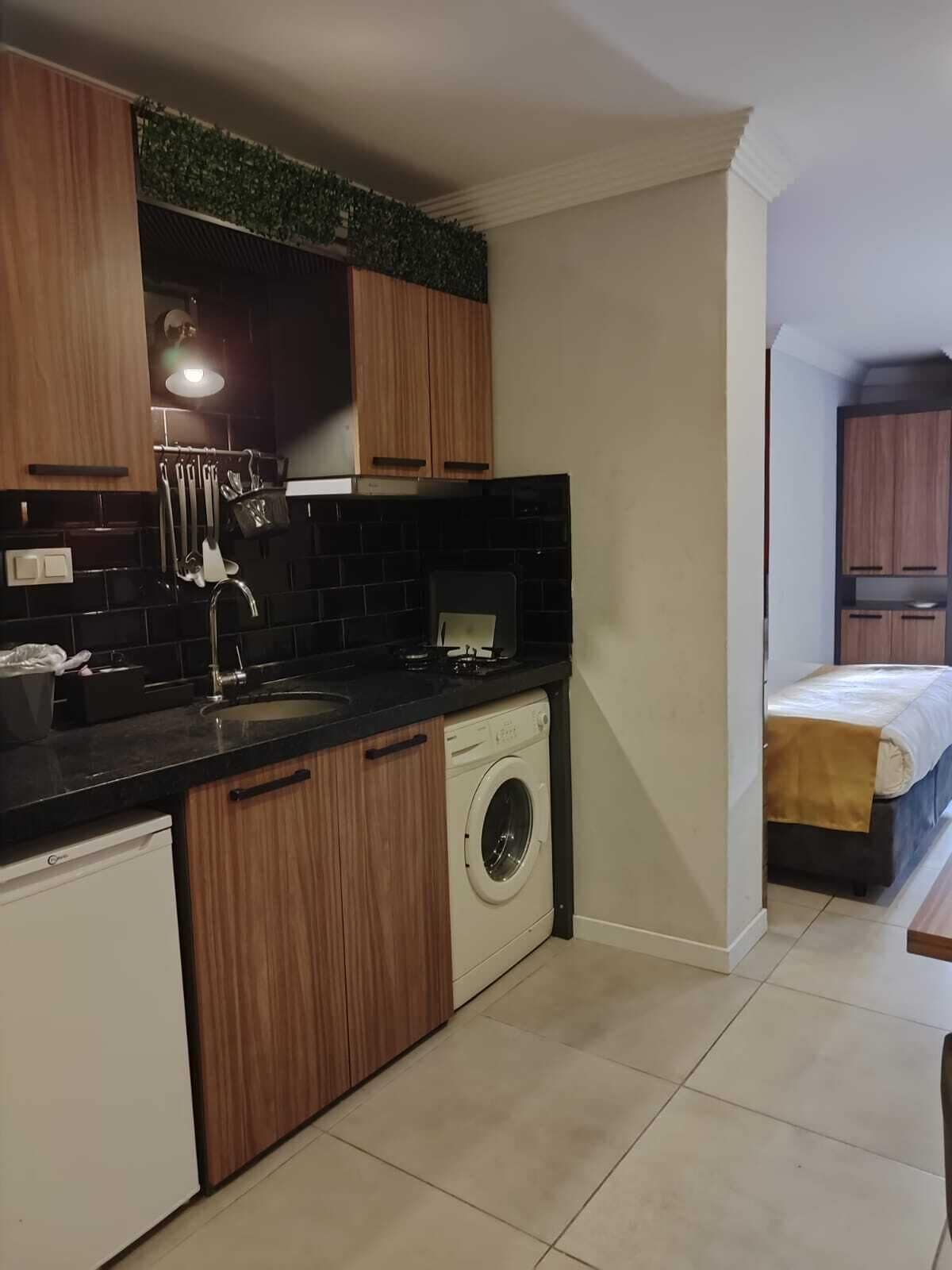 A compact kitchen with wooden cabinets, a washing machine, and a small countertop.
