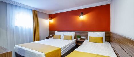 A hotel room with two beds, a wooden headboard, a large window with curtains, and wall-mounted lights.