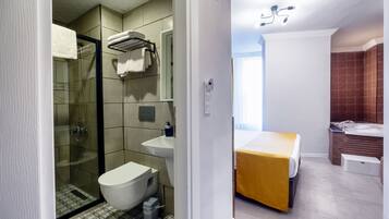 Un baño moderno con ducha de vidrio, inodoro blanco, lavamanos y cama con cubierta amarilla.