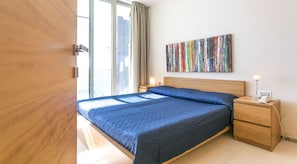 Un dormitorio con cama, mesita de noche de madera y un cuadro en la pared.