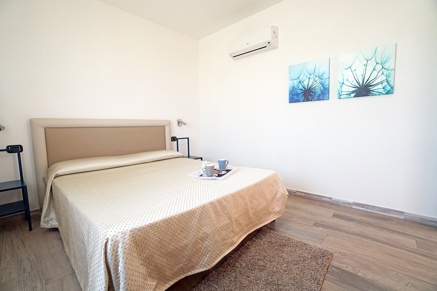 Una camera da letto con un letto, un comodino con una tazza e due elementi decorativi a parete.