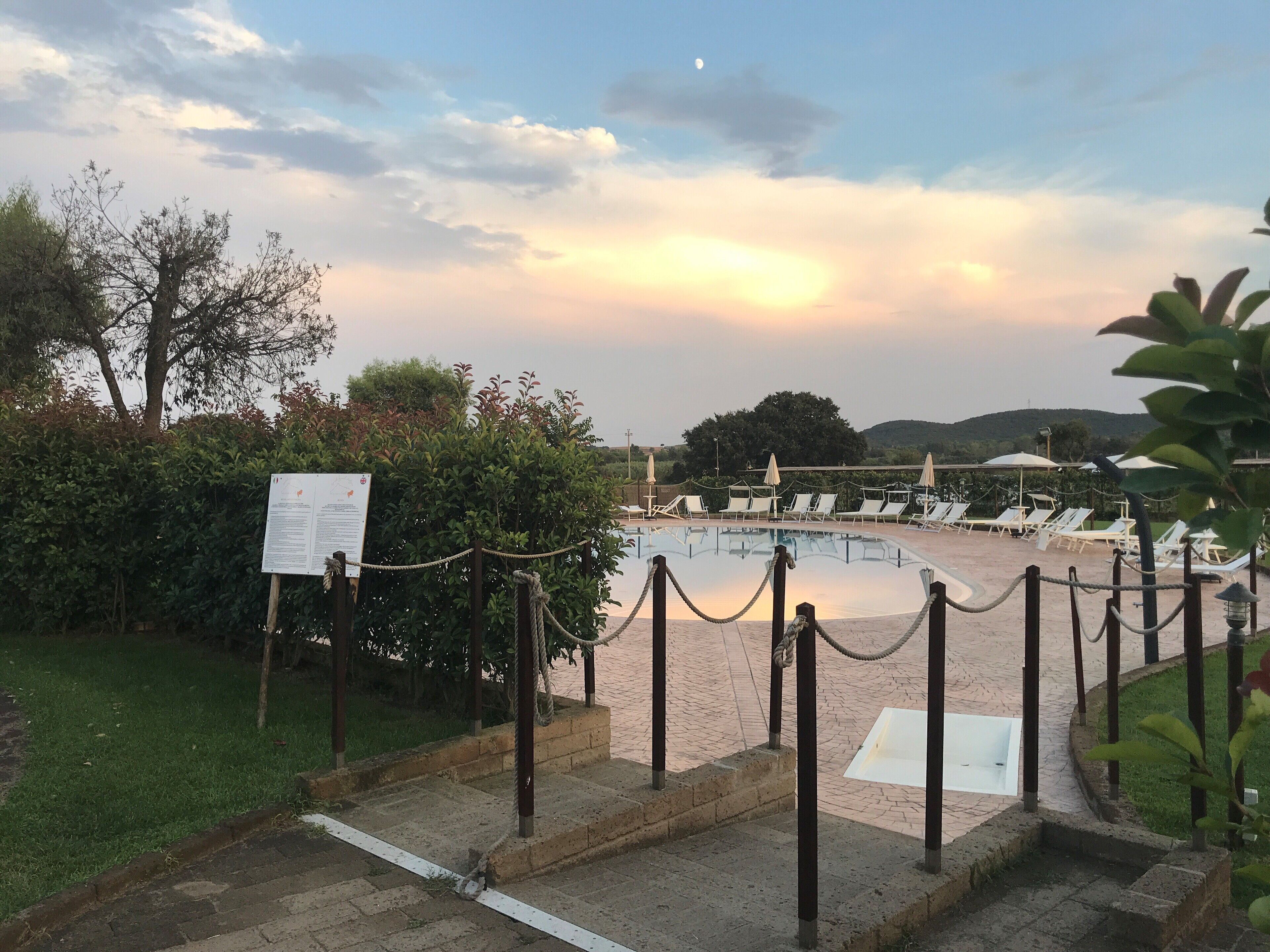 Area piscina con lettini, una barriera di corda e un cartello.