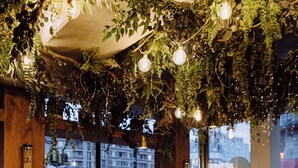 An indoor dining area with a round table, chairs, and a bench. The space is decorated with hanging plants and string lights. - La Belle Ville (Paris)