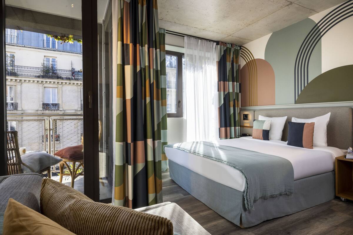 A hotel room with a large bed, a sofa, and a view of the city.