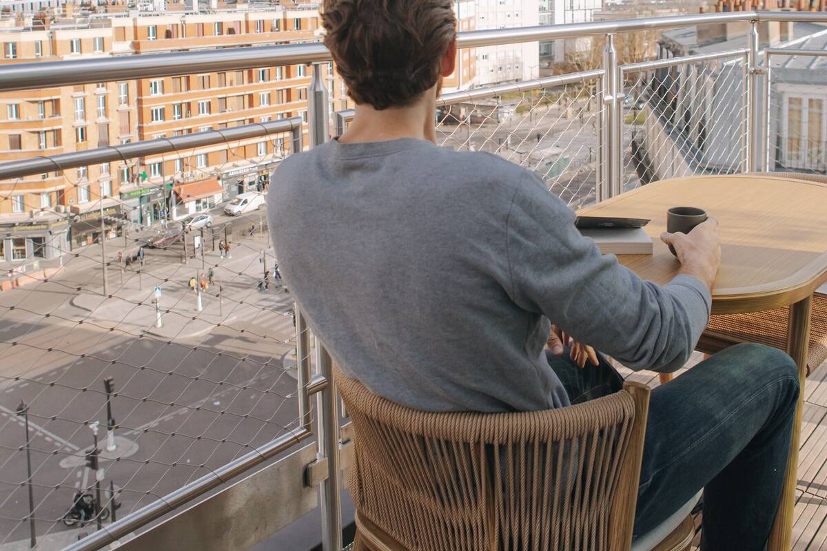 A person seated at a table with a view of a cityscape, including buildings and a crane.