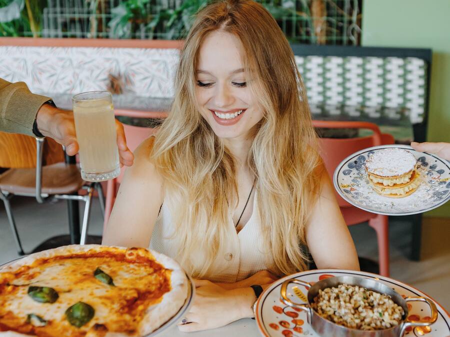Iemand zit aan een tafel met pizza en een dessertborden.
