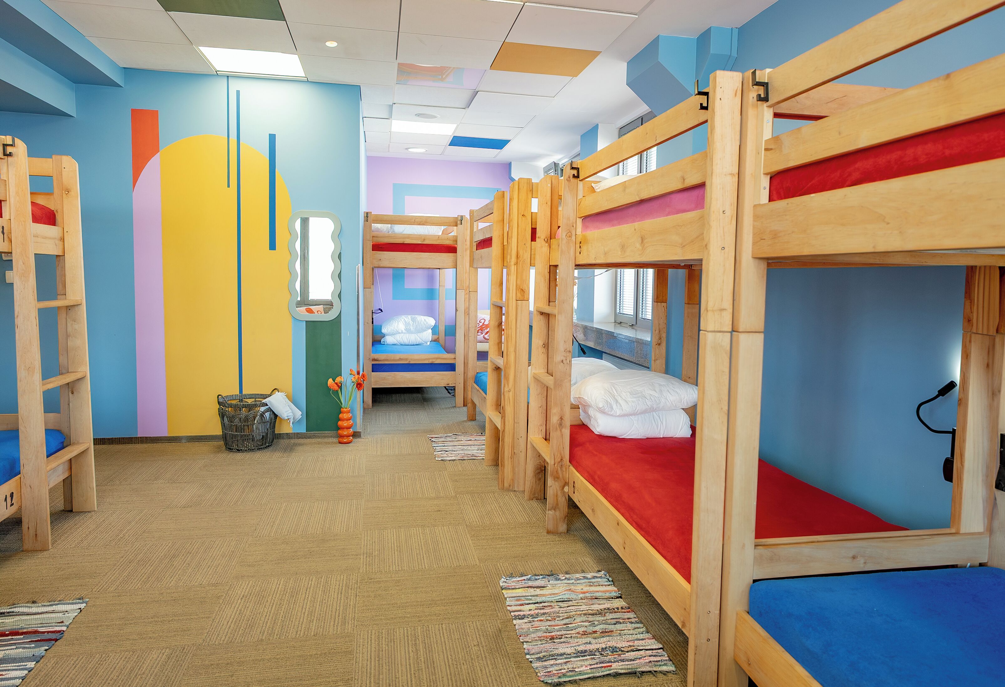 A children's room with bunk beds, a colorful wall, and a window.