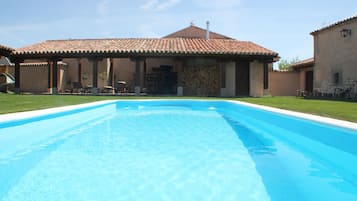 Een buitenzwembad, ligstoelen bij het zwembad