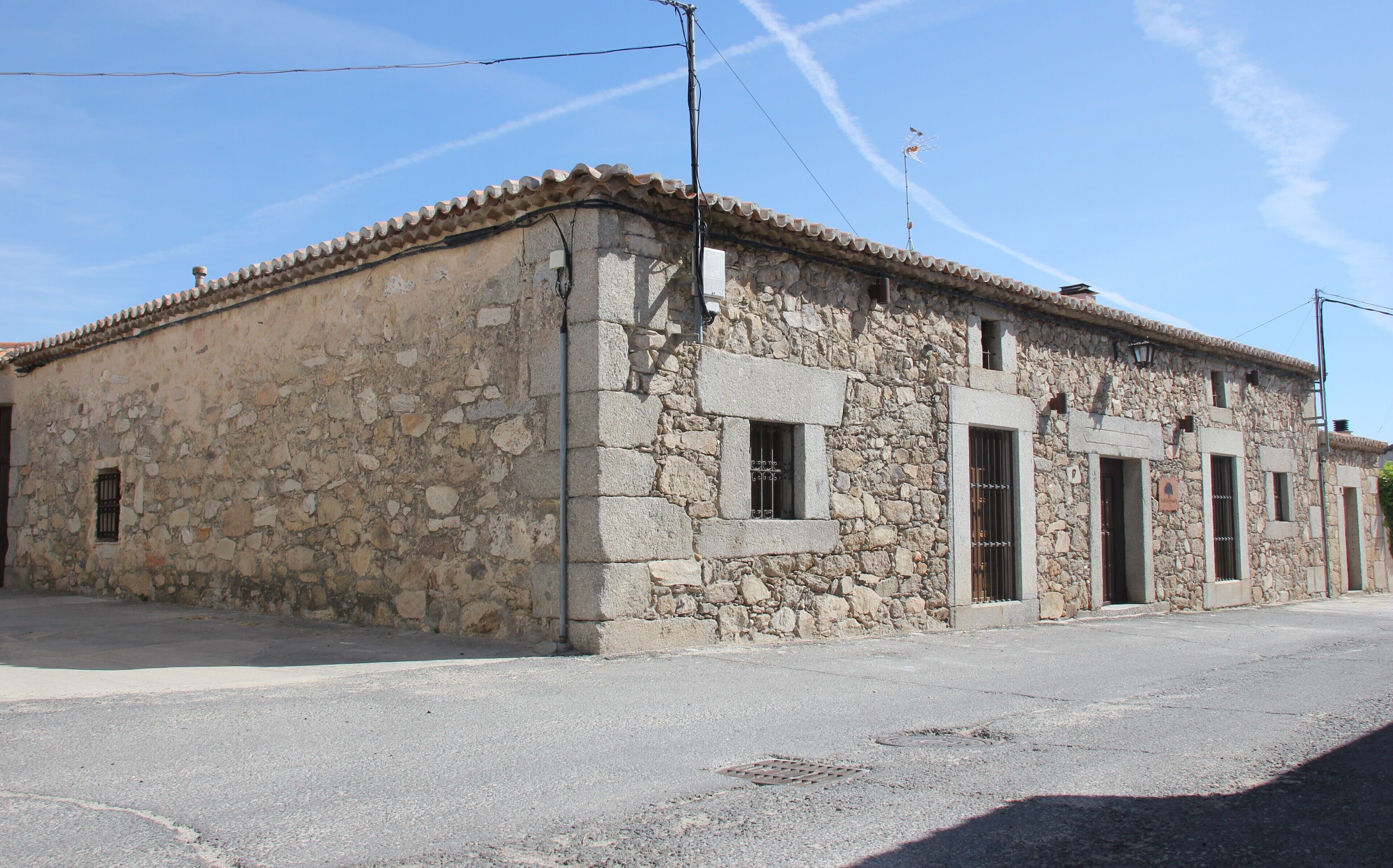 A stone building with a tiled roof, rectangular windows, and a small door.