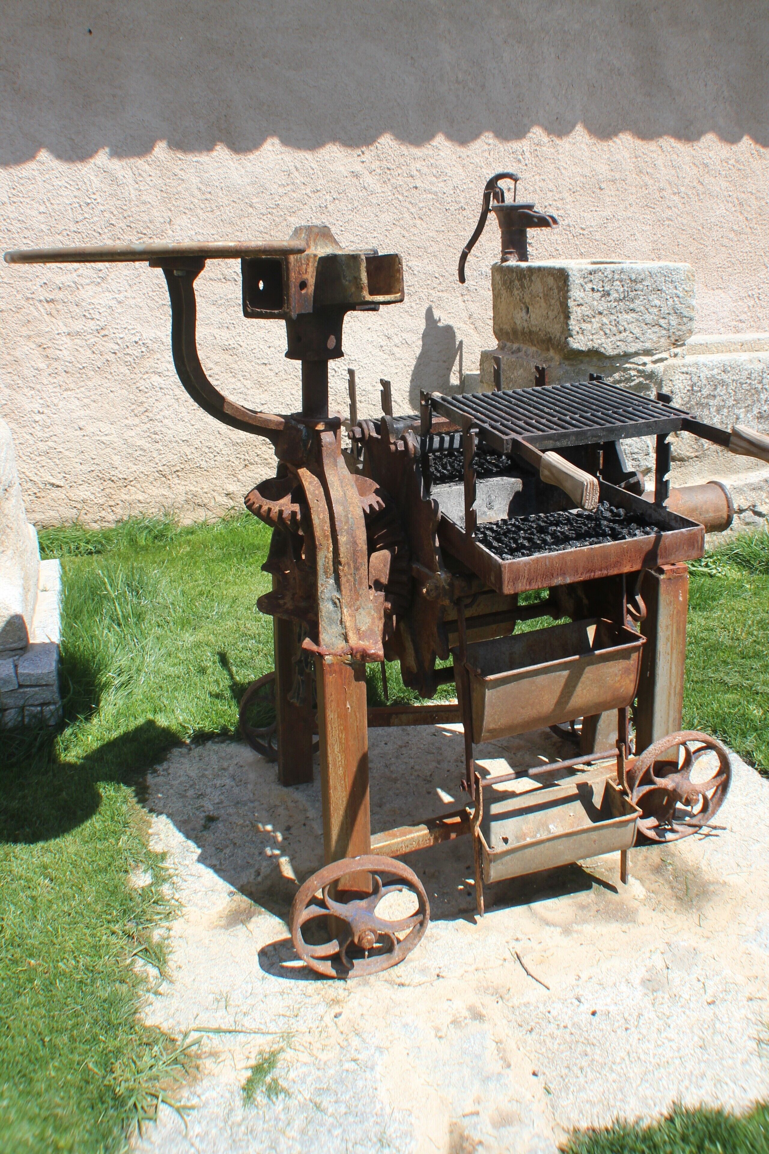 An old-fashioned, rusted mechanical device with wheels and a lever, possibly a historical piece of equipment.