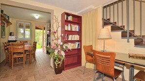 A dining area with a wooden table and chairs, a red bookshelf, and a staircase. - Casa D'amelia (Camaiore)