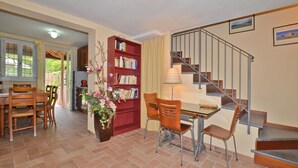 A dining area with a table and chairs, a bookshelf, and a staircase. - Casa D'amelia (Camaiore)