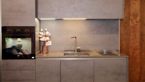 A modern kitchen with a built-in oven, a stainless steel sink, and a vase with flowers on the countertop. - Luxury apartment in Rione Monti (Roma)