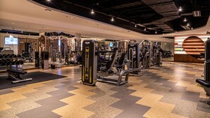 Un gimnasio moderno con varios equipos de ejercicio, un muro con espejos y un suelo a cuadros.