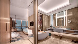 Habitación de hotel moderna con una bañera curva grande, un espejo amplio y vistas a la ciudad.