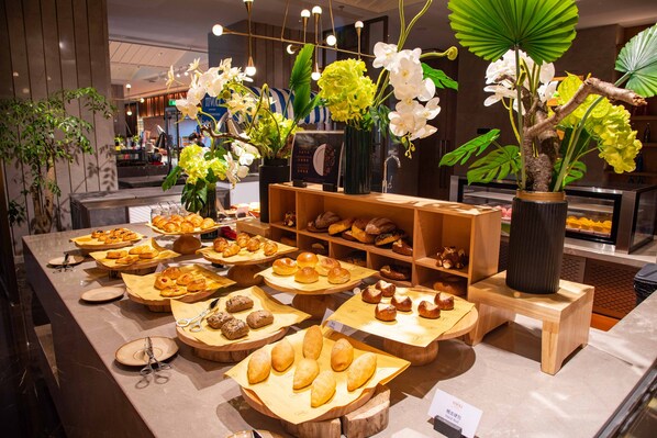 Een bakkerijvitrine met diverse gebakjes en een decoratieve plantenpresentatie.