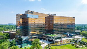 Een modern gebouw met een glazen gevel, aangeduid met 'TIVOLI', met een ruime entree en omliggend groen.