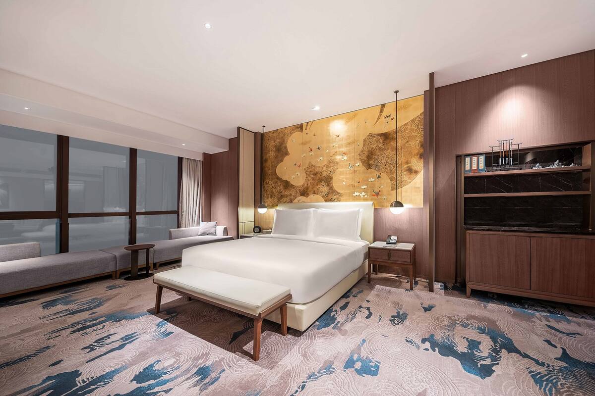 Une chambre d’hôtel moderne avec un grand lit, un canapé, une petite table et un téléviseur.