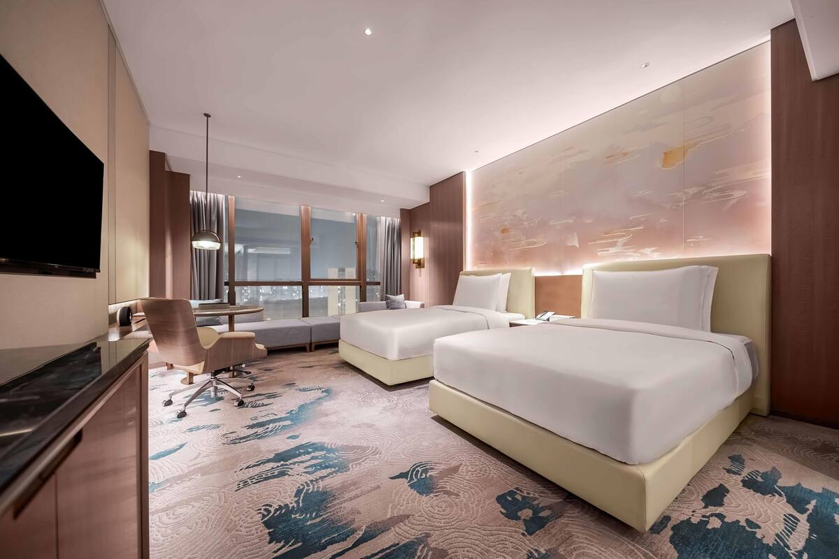 Une chambre d’hôtel moderne avec deux lits, un bureau et un canapé.