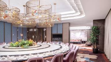 A modern dining area with a round table set for a meal, surrounded by plush chairs.