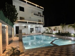 Ein zweistöckiges Gebäude mit Swimmingpool und überdachter Terrasse.