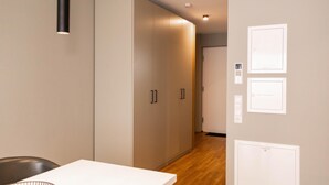 A hallway with a white table, a black chair, and a wardrobe. There are light switches and a door on the wall. - Chic apartment - Überlingen on Lake Constance (Überlingen)