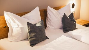 A neatly made bed with white and dark grey pillows, a wooden headboard, and a wall-mounted light fixture. - Chic apartment - Überlingen on Lake Constance (Überlingen)