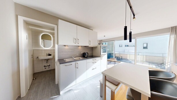 A modern kitchen with white cabinets, a built-in oven, and a large window overlooking a balcony. - Chic apartment - Überlingen on Lake Constance (Überlingen)