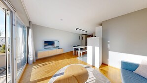 A modern living room with a flat-screen TV, a dining area with a table and chairs, and a sofa. - Chic apartment - Überlingen on Lake Constance (Überlingen)