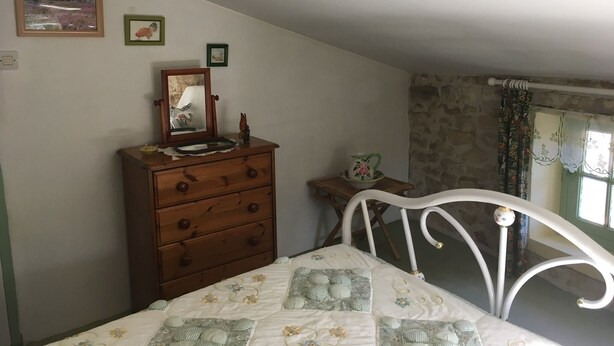 Ein Schlafzimmer mit einem Bett, einem Schminktisch, einem Spiegel und einem Fenster mit Vorhängen.