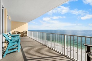 A balcony with a view of the ocean, featuring a railing, a table, and two chairs. - Beachfront in Gulf Shores w/ Gulf Views | Pool | Sauna | Sleeps 8 (Gulf Shores)