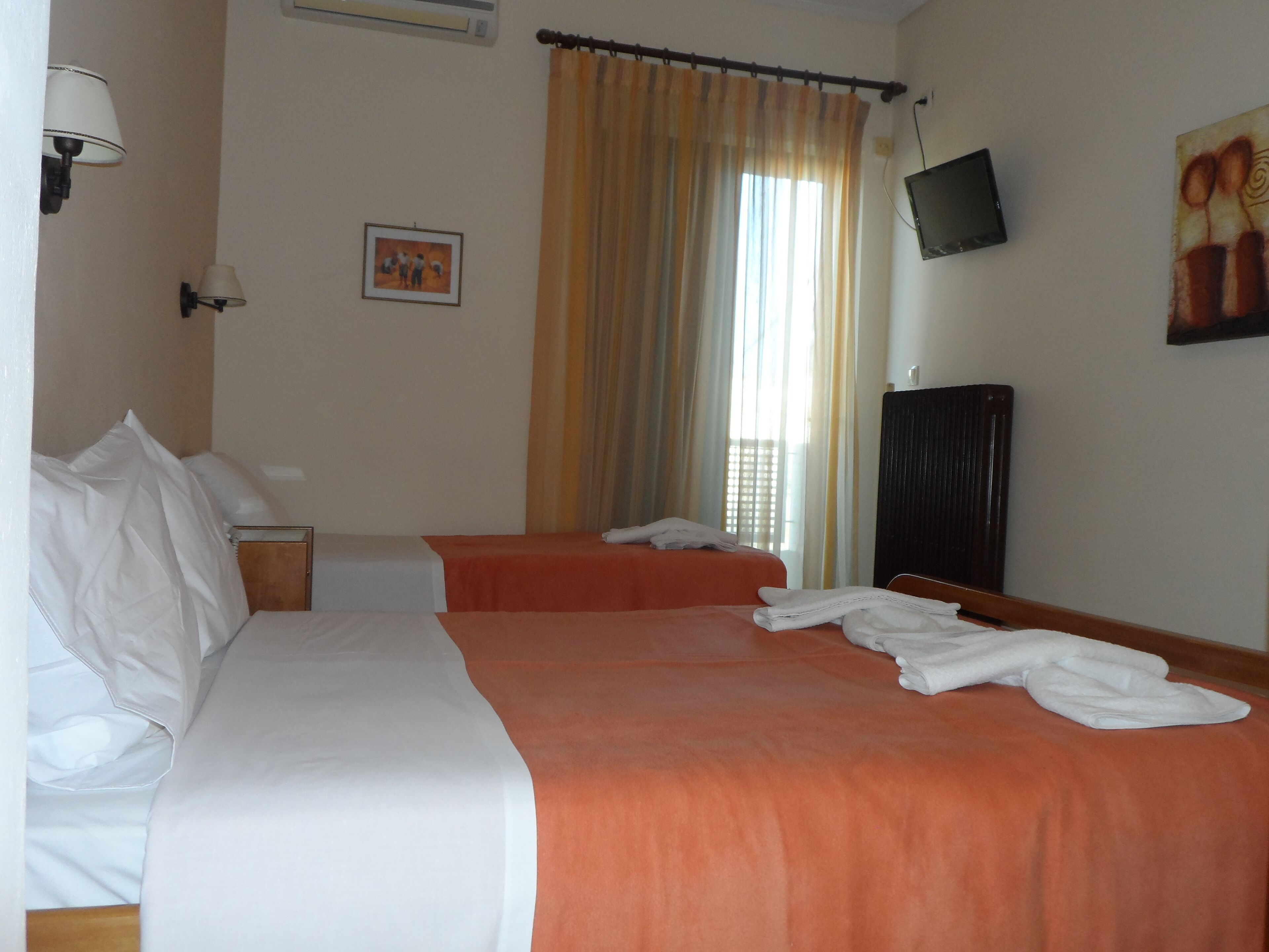 Habitación de hotel con dos camas, un televisor y un cuadro en la pared.