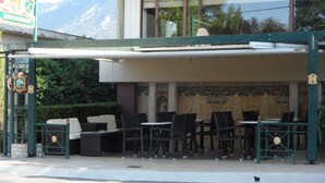 Ein Sitzbereich im Freien mit Korbmöbeln und einer überdachten Terrasse.