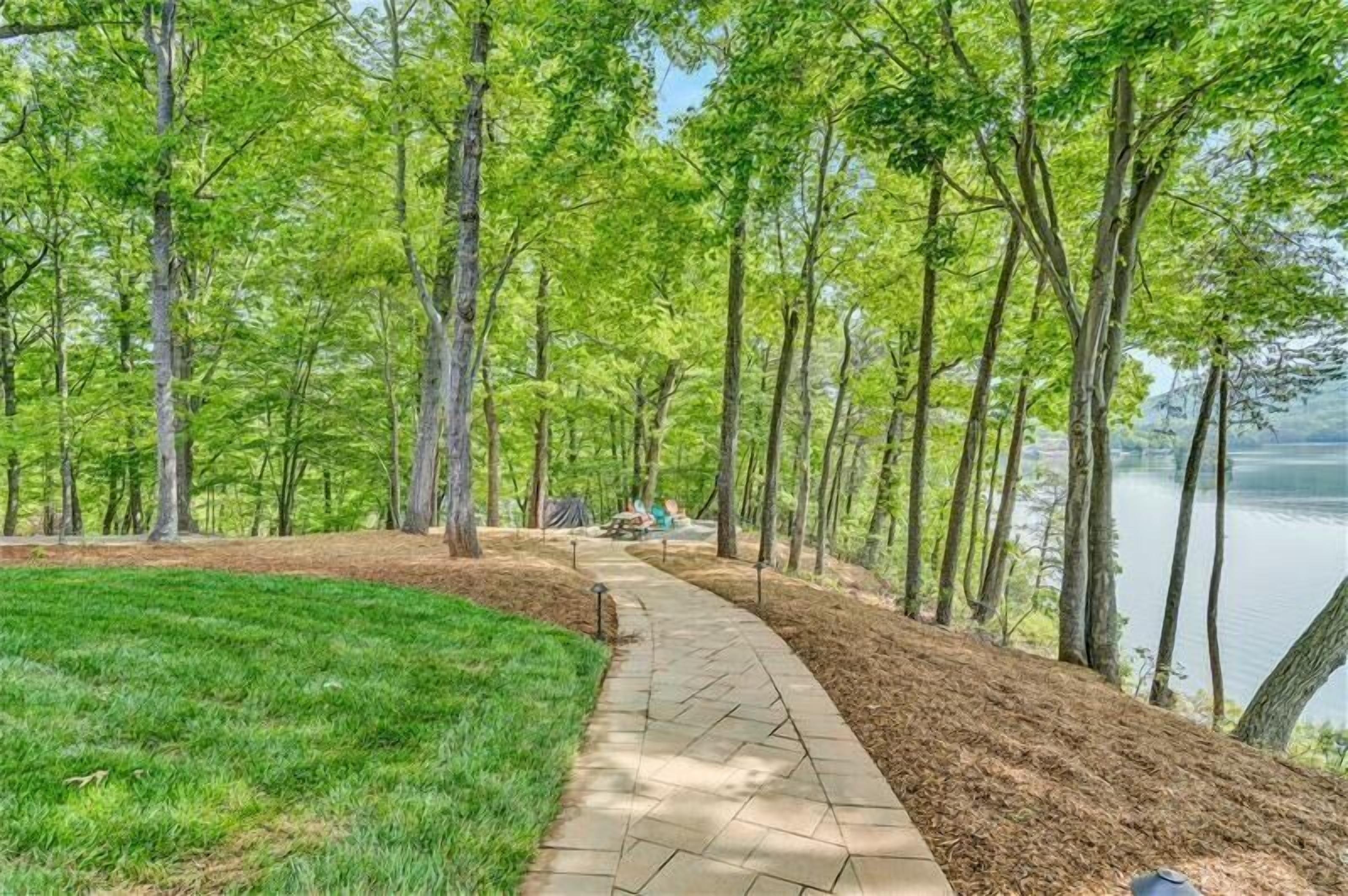 A paved walkway surrounded by trees and a lake.