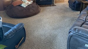 A living room with a fireplace, a television, and a cozy seating area with a bean bag and a couch. - Creekside Tranquility • Peaceful, Spacious Montana Home Near Missoula -20 Min (Florence)
