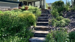 A covered porch with outdoor seating and a staircase leading to the entrance. - Creekside Tranquility • Peaceful, Spacious Montana Home Near Missoula -20 Min (Florence)