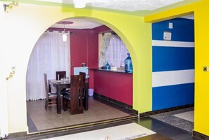 A dining area with a table and chairs, a water dispenser, and a window with curtains. - Delight Mainstay Homes by Della (Nairobi)