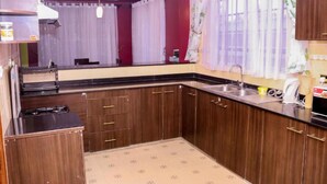 A compact kitchen with wooden cabinets, a sink, and a countertop. - Delight Mainstay Homes by Della (Nairobi)