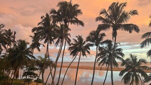 Een strand met palmbomen en een zonsondergang.