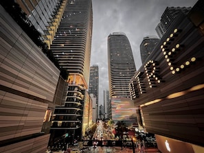 A modern urban street with tall buildings, a busy intersection, and a pedestrian walkway.