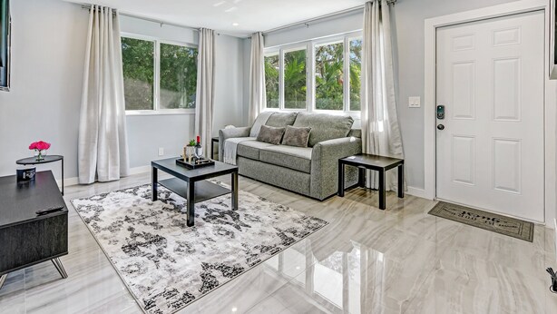 A modern living room with a sofa, coffee table, and side tables. - Hallandale 1037 | Lakeside View: 15KM to Stadium & Near Beach (Hallandale Beach)