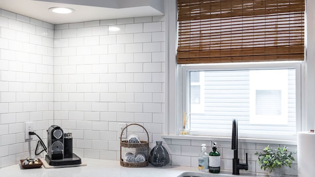 A kitchen with white subway tiles, a coffee maker, a basket, a vase, and a window with blinds. - City Boho ✦ New Kitchen ✦ King Bed (Bexley)