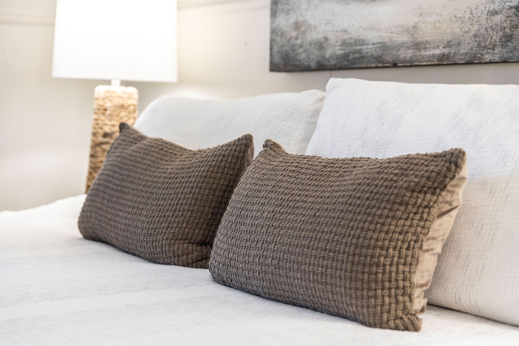 Ein Bett mit zwei strukturierten Kissen und einem schlichten, weißen Kopfteil.