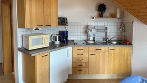Eine kleine Küche mit Holzausstattung, einer Mikrowelle, einer Kaffeemaschine und einem Toaster.