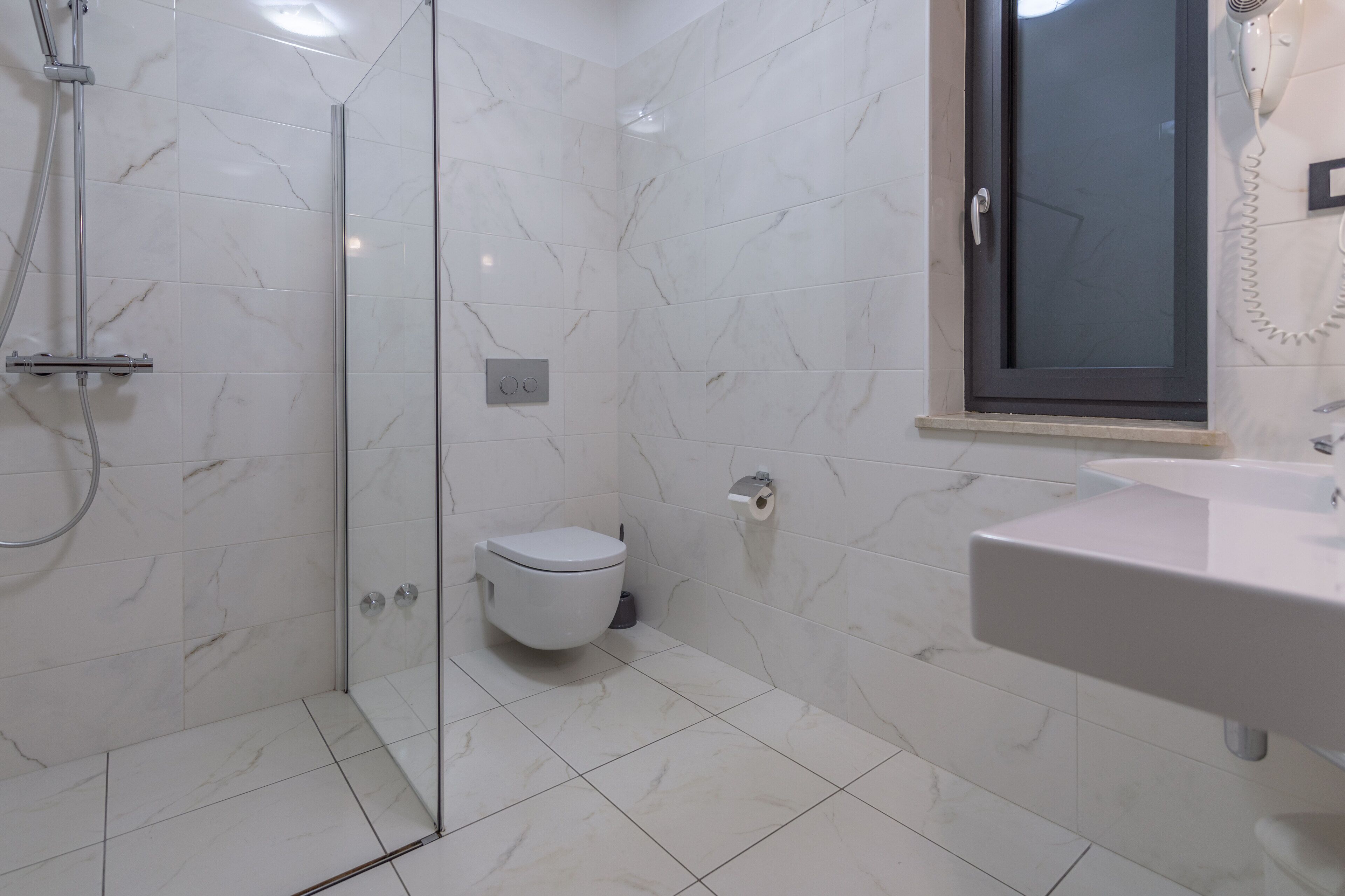 Un bagno con doccia vetro, un water e un lavandino.