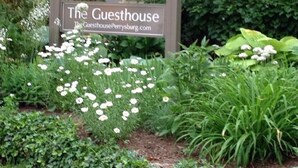 Señal de 'The Guesthouse' con un jardín al frente.