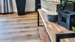 Una sala de estar moderna con un banco de madera, una planta grande en maceta y una pila de cestas tejidas.